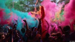Competitors listen to a DJ set and throw packets of coloured powder after finishing the Color Run