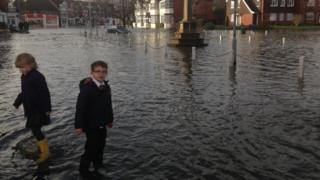 A couple of children in the floodwater wearing wellies