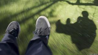 shadow of a boy on a swing on grass