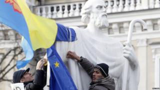Protesters tie an EU flag to a statue