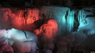 A partially frozen American Falls is seen lit by lights during sub freezing temperatures in Niagara Falls, Ontario