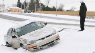 A man walks away from a vehicle after it ran off the icy road