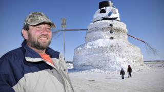 Greg Novak stands next to the giant 50-foot snowman he's created in Minnesota.