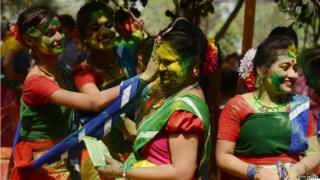 Two girls smear another with powder paint