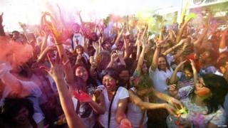 A crowd of people throwing powder paint for Holi