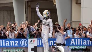 Mercedes driver Lewis Hamilton of Britain stands on his car.