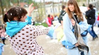 People dressed up in their pyjamas having a pillow fight