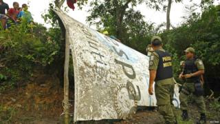 People stood around a large piece of metal amongst bushes. The metal has UK SPACE AGENCY written on it.