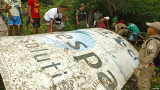 People stood around a large piece of metal amongst bushes. The metal has UK SPACE AGENCY written on it.