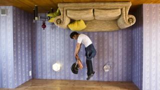 Man jumps inside upside-down house.
