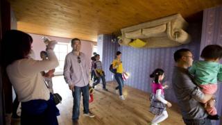 Woman takes photo in upside-down house.