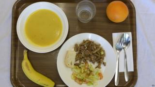 The lunch is composed of cream of vegetable soup, pan-fried breast of veal with salad, a piece of bread, an orange or banana and water.