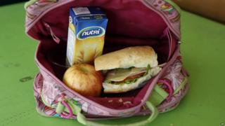 The lunch consists of a sandwich of ham, cheese, tomato and lettuce, a boxed oatmeal drink, and an apple.