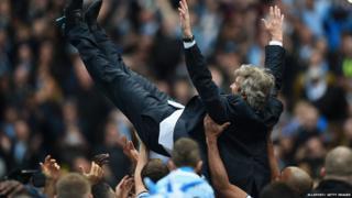 Players lift Manuel Pellegrini after winning the premier league title