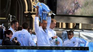 Vincent Kompany holding trophy on top of bus