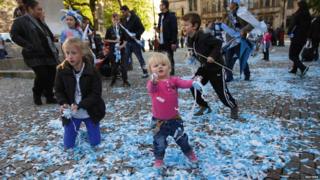 Fans playing with blue and white confetti