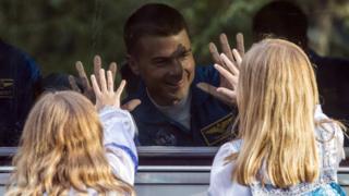 US Astronaut Reid Wiseman waves to his daughters through the window of the bus as he heads to base for final pre-flight preparations.