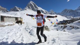 Runner Francis Kersten smiles and waves flags as he runs near the start.