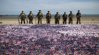 Military enthusiasts stand in front of thousands of flags.