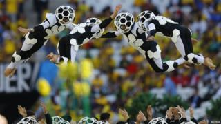 Dancers dressed as footballs leaping into the air