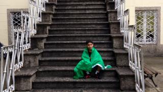 Boy sat on stairs with flag around him