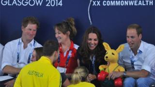Prince Harry looks on as Kate and William receive a toy kangaroo from Australian swimmers at Tollcross swimming pool