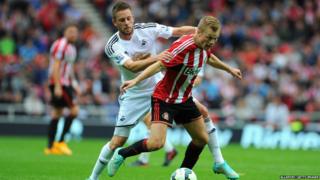 Swansea player Gylfi Sigurdsson challenges Sebastian Larsson of Sunderland during the Barclays Premier League match between Sunderland and Swansea City at Stadium of Light