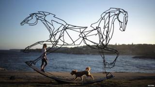 Dog running past sculpture