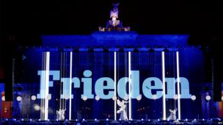 The word peace projected on the Brandenburg Gate.
