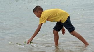 A boy lays a flower in water