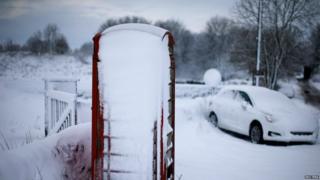 An abandoned car and a telephone box stand in snow near Ashbourne, central England December 27, 2014.