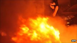 A woman passes a fire during protests Thessaloniki, 10 September