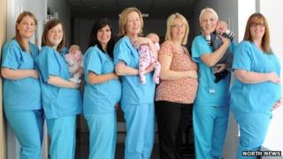 Seven midwives pose with bumps and babies