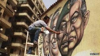 An artist paints the faces of Amr Moussa and Ahmed Shafiq and a combination of the faces of former president Hosni Mubarak and Field Marshal Mohamed Hussein Tantawi in Cairo May 22, 2012