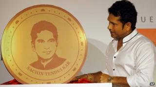 Sachin Tendulkar looks at a replica of a gold coin embossed with his face in Mumbai on May 13, 2013