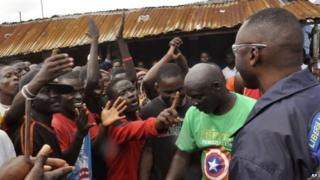 A Liberian policeman, right, speaks with residents of the West Point in Monrovia