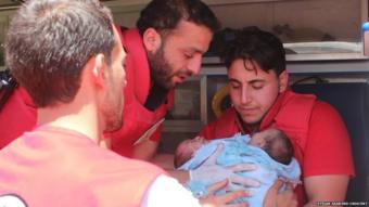 Red Crescent workers hold the babies