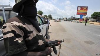 A militia man stands guard at a checkpoint in Abidjan in 2011