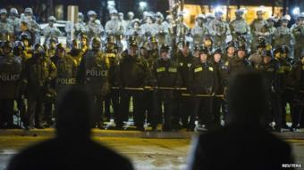 Protesters stare at a line of police officers and National Guard soldiers during a protest to demand justice for the killing of 18-year-old Michael Brown