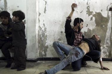 A man gives medical assistance to an injured man after what activists said was an air strike by government forces the Duma district of Damascus, Syria (2 February 2015)