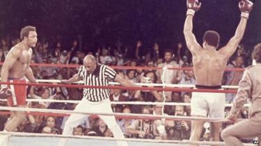 Muhammad Ali, arms raised in victory, walks to his corner as referee Zack Clayton counts out George Foreman after Ali knocked him down in the eighth round of their Rumble in the Jungle