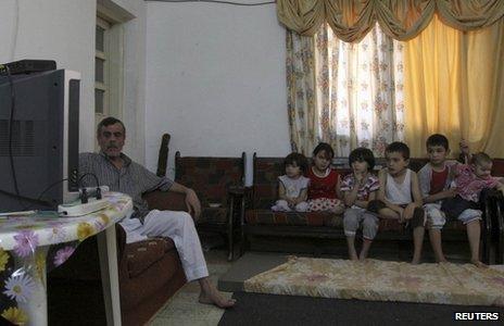 A family of Syrian refugees watch television