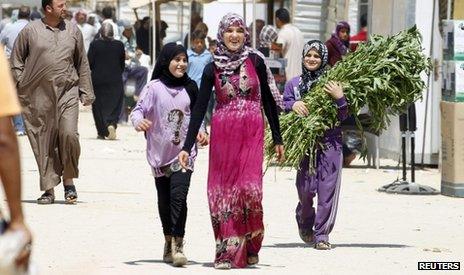 Syrian refugees walk on the main market street at Al-Zaatri refugee camp