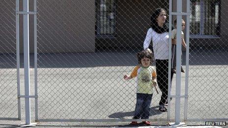 Hevin Youseff, a 28-year-old Syrian woman, walks with her children behind a fence at a detention centre