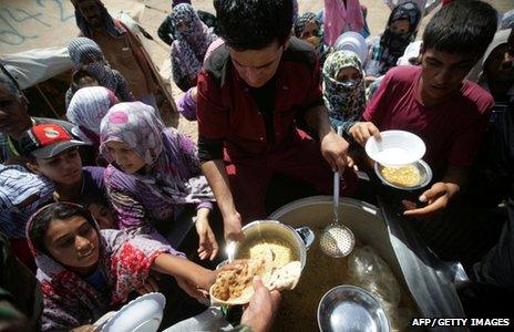 Syrian-Kurdish refugee families queue to get food