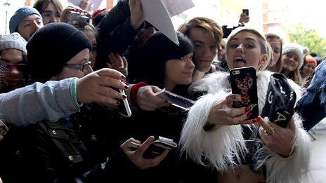 Miley Cyrus poses with fans
