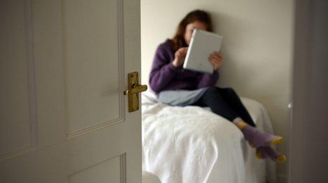 Girl with a tablet sitting on a bed
