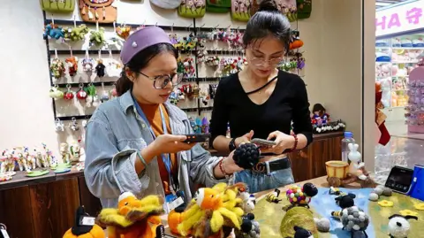 Two women shop for soft toys in a souvenirs shop in China.