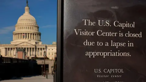 The Capitol in the background with a black sign saying the U.S. Capitol Visitors Center is closed to due to a lapse in appropriations in the foreground. 