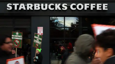 People hold signs outside of a Starbucks Coffee store.